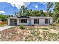 Charming single-story home with a white painted exterior, black trim, and blue front door at 6820 Se 108Th St, Belleview, FL 34420