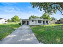 Charming home with a well-manicured lawn, long driveway, and covered front porch with a lovely country motif at 8973 Sw 103Rd Ln, Ocala, FL 34481