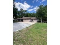 Sprawling single story home featuring multiple garage doors surrounded by mature trees and landscaping at 1325 Nw 73Rd Ter, Ocala, FL 34482