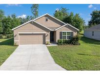 Charming single-story home featuring a well-manicured lawn, attached garage, and neutral-toned exterior at 160 Hickory Course Loop, Ocala, FL 34472