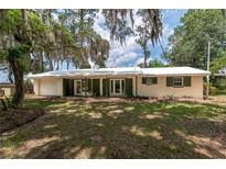 Charming single-story home with a lush lawn, bright exterior, and welcoming double doors at 23797 Ne 189Th St, Fort Mc Coy, FL 32134