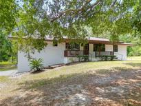 Charming single-story home with a well-maintained lawn and a inviting front porch, nestled under a shady tree at 2580 Se 157Th Lane Rd, Summerfield, FL 34491
