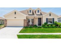 Charming single-Gathering home featuring a well-manicured lawn, complemented by stone accents and a two-car garage at 5248 Red Coral Cir, Mount Dora, FL 32757