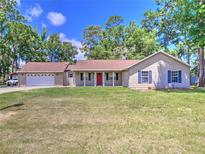 Charming single-story home with a well-maintained lawn and a bright red front door at 5410 Nw 62Nd Ave, Ocala, FL 34482