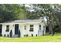 Charming white home with a dark blue front door, small front yard, black fence and mature trees at 1705 Nw 18Th Ave, Ocala, FL 34475