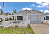 Charming single-story home with a well-manicured lawn and a white picket fence under a sunny blue sky at 2608 Botello Ave, The Villages, FL 32162