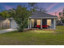 Charming single-story home with cozy front porch featuring red outdoor furniture and well-maintained lawn at 30 Bahia Trace Loop, Ocala, FL 34472