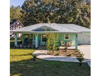 Charming teal home featuring a metal roof, inviting front porch, and well-maintained front lawn at 9330 Se 106Th Pl, Belleview, FL 34420