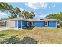 Charming single-story home features a blue exterior, attached garage, and well-kept lawn at 11 Se Fir Trail Trak, Ocala, FL 34472