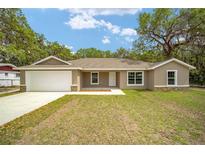 Charming single-story home with a two-car garage and a well-maintained front yard at 1143 Sw Tamiami Pl, Dunnellon, FL 34431