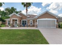 Charming single-story home with a well-manicured lawn, stone accents, a two-car garage, and a paver driveway at 12804 Se 90Th Court Rd, Summerfield, FL 34491