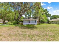 Charming home featuring a quaint screened porch and a spacious, tree-shaded front yard at 1405 Ne 55Th St, Ocala, FL 34479