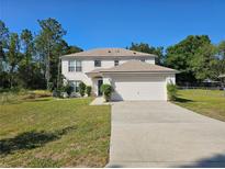 Two-story home with a well-maintained lawn and an attached two-car garage on a sunny day at 18 Fir Trail Dr, Ocala, FL 34472