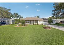 Charming single-story home with a well-manicured lawn and mature landscaping at 2208 Orkney Dr, Leesburg, FL 34788