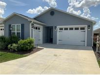 Charming single-story home with blue siding, a two-car garage, and well-maintained landscaping at 2296 Sheehan St, The Villages, FL 32163