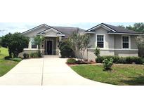 Charming single-story home featuring a well-manicured lawn, lush landscaping, and a paved driveway leading to the front entrance at 4990 Sw 63Rd Loop, Ocala, FL 34474