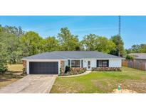 Charming single-story home with a stone facade, dark garage door, and manicured front yard at 6 Bahia Circle Loop, Ocala, FL 34472
