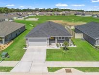 New construction home boasts gray tones, a modern landscape, and a well-maintained lawn in a suburban neighborhood at 16192 Se 104Th Ter, Summerfield, FL 34491