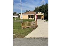 Charming single-story home featuring a well-maintained lawn, and a quaint decorative fence at 24 Malauka Ter, Ocklawaha, FL 32179
