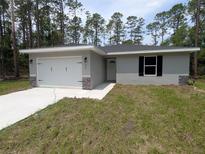 Charming single-story home with a two-car garage, featuring stone accents and a well-maintained front lawn at 960 Nw Redwood Dr, Dunnellon, FL 34431