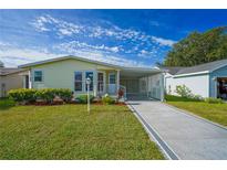 Charming single-story home with well-manicured lawn, carport and walkway under a bright blue sky at 1228 Maria Ct, Lady Lake, FL 32159