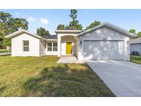 Charming single-story home featuring a bright yellow door and attached two-car garage at 12988 Se 42Nd Ct, Belleview, FL 34420