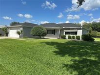 Charming single-story home featuring a well-manicured lawn, mature landscaping, and attached two-car garage at 14117 Sw 115Th Cir, Dunnellon, FL 34432