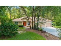 Inviting single-story home with a well-manicured lawn and colorful orange front door at 18328 Sw 73Rd Loop, Dunnellon, FL 34432