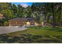 Beautiful single-story home featuring a circular driveway, lush landscaping, and mature trees at 200 Se 145Th St, Summerfield, FL 34491