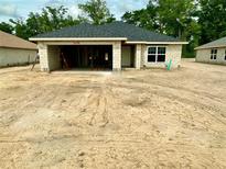 New construction home featuring block exterior, grey roof, and large open garage on a spacious lot at 3155 Ne 46Th Ave, Ocala, FL 34470