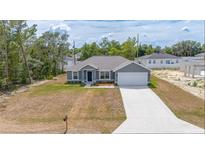 Charming gray home with a well-manicured lawn and a freshly poured concrete driveway at 400 Mariion Oaks Crse, Ocala, FL 34473