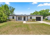 Charming single-story home featuring a dark metal roof, black trim, fresh white siding, and a well-maintained lawn at 4095 Sw 144Th St, Ocala, FL 34473