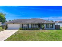 Charming one-story home featuring a well-maintained lawn, classic windows with shutters, and an attached garage at 7 Larch Dr, Ocala, FL 34480