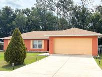 Single-story home with a two-car garage, orange stucco exterior, and well-manicured lawn at 14 Dogwood Drive Radl, Ocala, FL 34472