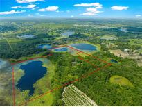 Expansive aerial view of the property with lush landscapes, several lakes, and mature trees at 17150 Se 168Th Ter, Weirsdale, FL 32195