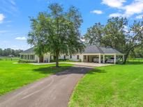 Expansive home featuring a covered portico and manicured lawn with a long driveway at 402 Sw 127Th Pl, Ocala, FL 34473