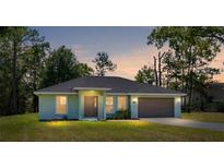 Inviting single-story home featuring a well-manicured lawn, a two-car garage, and a charming front entrance at 5425 Pecan Rd, Ocala, FL 34472