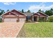 Charming single-story home with a three-car garage, beautiful landscaping, and a brick-paved driveway at 6680 Sw 179Th Court Rd, Dunnellon, FL 34432