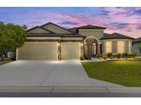 Beautiful home exterior with a two-car garage, stone accents, and well-manicured landscaping under a colorful sky at 9777 Sw 63Rd Loop, Ocala, FL 34481