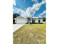 Charming single-story home featuring a two-car garage and a well-maintained lawn under a bright, cloudy sky at 12282 Sw 80Th St, Dunnellon, FL 34432