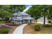 A beautiful two-story home with gray siding, porch, porte-cochere, and three-car garage at 1628 Se 29Th Ter, Ocala, FL 34471