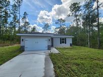 Charming one-story home with a two-car garage, surrounded by a lush green lawn and towering trees at 404 Nw Redwing Rd, Dunnellon, FL 34431
