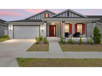 Charming home featuring a two-car garage, red door, front porch, and manicured landscaping at 6486 Sw 75Th Avenue Rd, Ocala, FL 34474