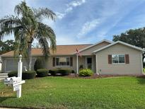 Charming single-story home with manicured lawn, lovely landscaping, and a beautiful palm tree at 9131 Se 135Th St, Summerfield, FL 34491