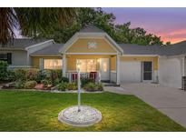 Charming yellow home featuring a well-manicured lawn and cozy front porch at 9290 Sw 89Th Ter # D, Ocala, FL 34481