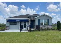 Charming single-story home featuring stone accents and a well-manicured lawn under a bright blue sky at 9354 Sw 60Th Terrace Rd, Ocala, FL 34476