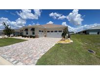 Inviting exterior of the home featuring a brick driveway and a two-car garage at 10287 Sw 96Th Ln, Ocala, FL 34481