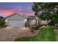 Charming single-story home featuring a manicured lawn, brick driveway, and well-maintained landscaping at dusk at 1748 Sw 157Th Place Rd, Ocala, FL 34473