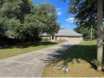 Charming home with a well-maintained lawn, mature trees, and a long driveway leading to a two-car garage at 21 Pecan Course Cir, Ocala, FL 34472