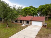 View of the house featuring a well-manicured lawn, long driveway, and a two-car garage at 346 Emerald Rd, Ocala, FL 34472